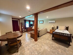 A room with a bed, a sofa, a dining table with chairs, a TV, and a bookshelf. - Cabin Fever in the foothills of the Blue Ridge Mountains  (Luray)