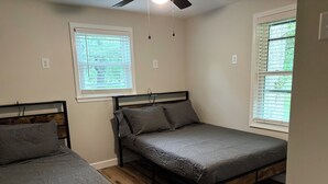 Quarto com duas camas, piso de madeira e janelas com persianas.