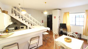 Une cuisine équipée d’un four à micro-ondes, d’un évier et d’un plan de travail. Un escalier mène à un autre niveau.