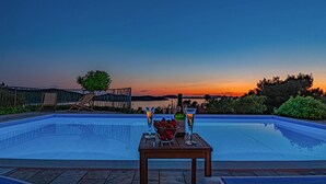 A poolside setting with a table set for two, a bottle of liquor, and a bowl of strawberries. - Beach front home in Zaboric (Zaboric)
