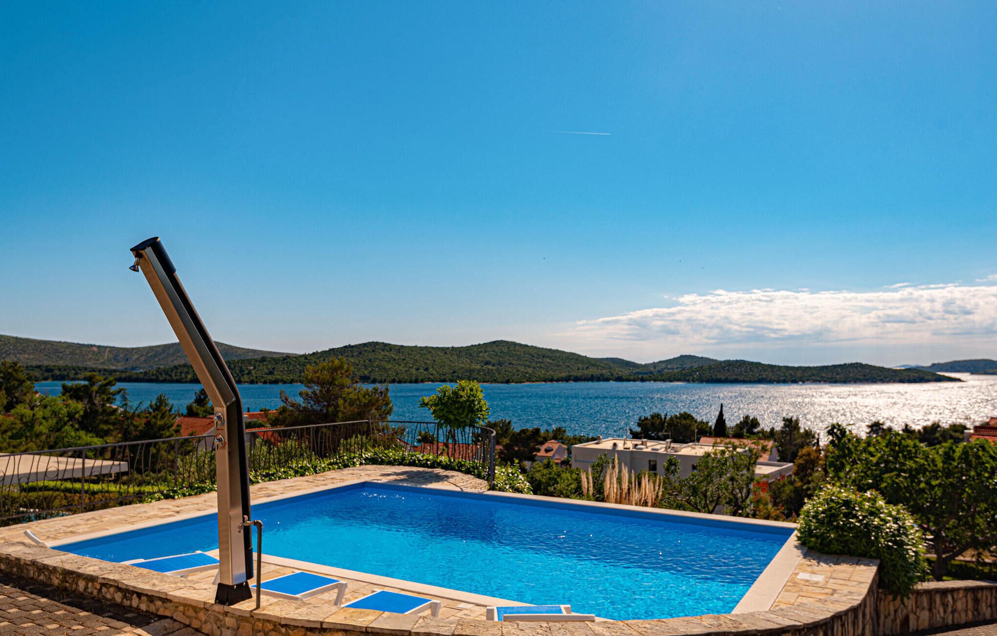 Una piscina con vistas a un lago y colinas al fondo.
