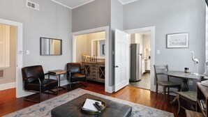 A spacious living room with a fireplace, a dining area with a wooden table, and a kitchen in the background.