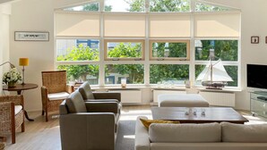 A modern living room with a high ceiling, large windows, a sailboat model, and a cozy seating area. - 3 bedroom luxurious home in Workum (Workum)