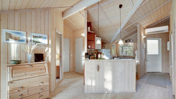 Un intérieur en bois comprenant un espace cuisine, des meubles de rangement en bois et un îlot central.