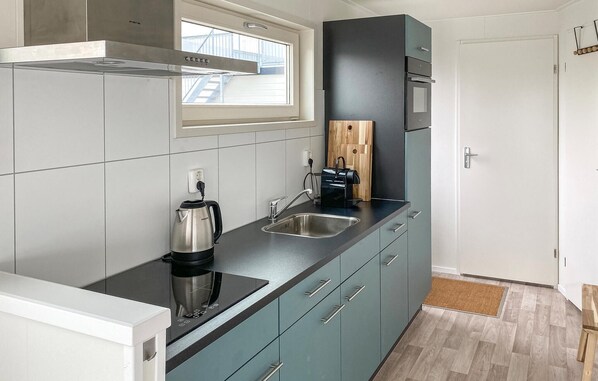 Une cuisine de taille réduite avec un plan de travail noir, des appareils en acier inoxydable et des meubles de couleur turquoise.