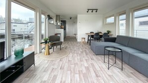 En moderne lejlighed med opholdsstue, spiseplads og udsigt over byen.