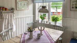 En matplats med ett bord dukat för två personer, en ljusstake och ett fönster med utsikt över en trädgård.