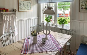 En matplats med ett bord dukat för två personer, en ljusstake och ett fönster med utsikt över en trädgård.