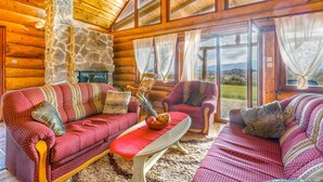 A cozy cabin interior with a stone fireplace, wooden walls, and a large window offering a scenic view. - Amazing home in Sveti Rok (Sveti Rok)