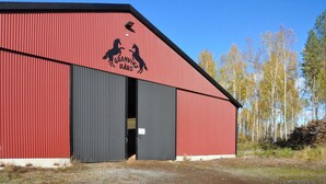 Punainen lato, jossa on musta ovi ja hevoskuvia sisältävä logo.