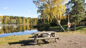 Piknikpöytä järven rannalla, lähellä kyltti, jossa kielletään uiminen.