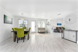 A spacious living area with a dining table, chairs, a sofa, and a coffee table.