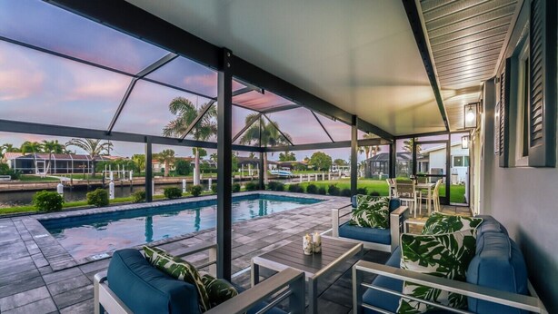 Ein überdachter Außenbereich mit Pool, Sitzgelegenheiten und Blick auf eine Wohngegend.