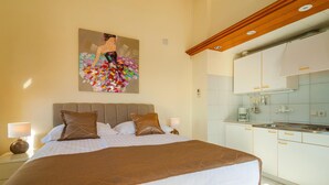 Una habitación de hotel con cama, un cuadro, una zona de cocina y un baño.