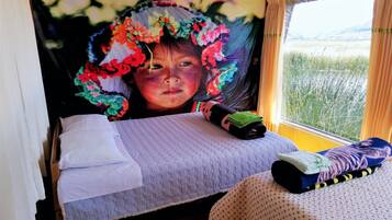 Relax in a serene bedroom with a large bed, vibrant tapestry, and a view of a lush field.