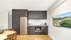 Een moderne keuken met donkerhouten kasten, een roestvrijstalen koelkast en een oven.