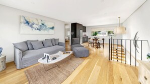 Een moderne woonkamer met een grijze bank, een salontafel en een trap met een leuning.
