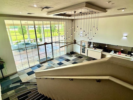 A modern interior with a staircase, a checkered floor, and a view through large windows.