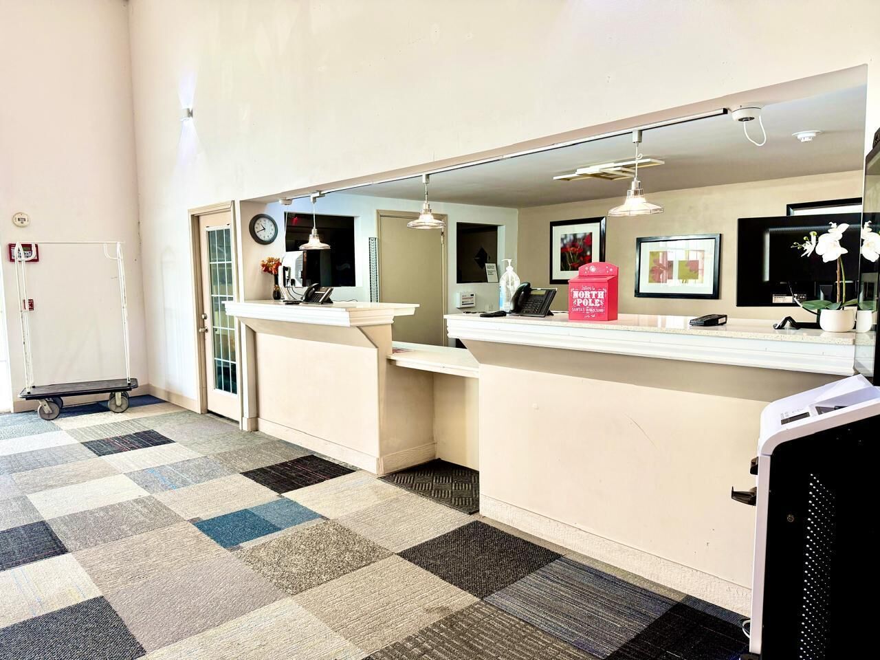 A reception area with a check-in counter, a clock, a phone, and a small desk with a chair.