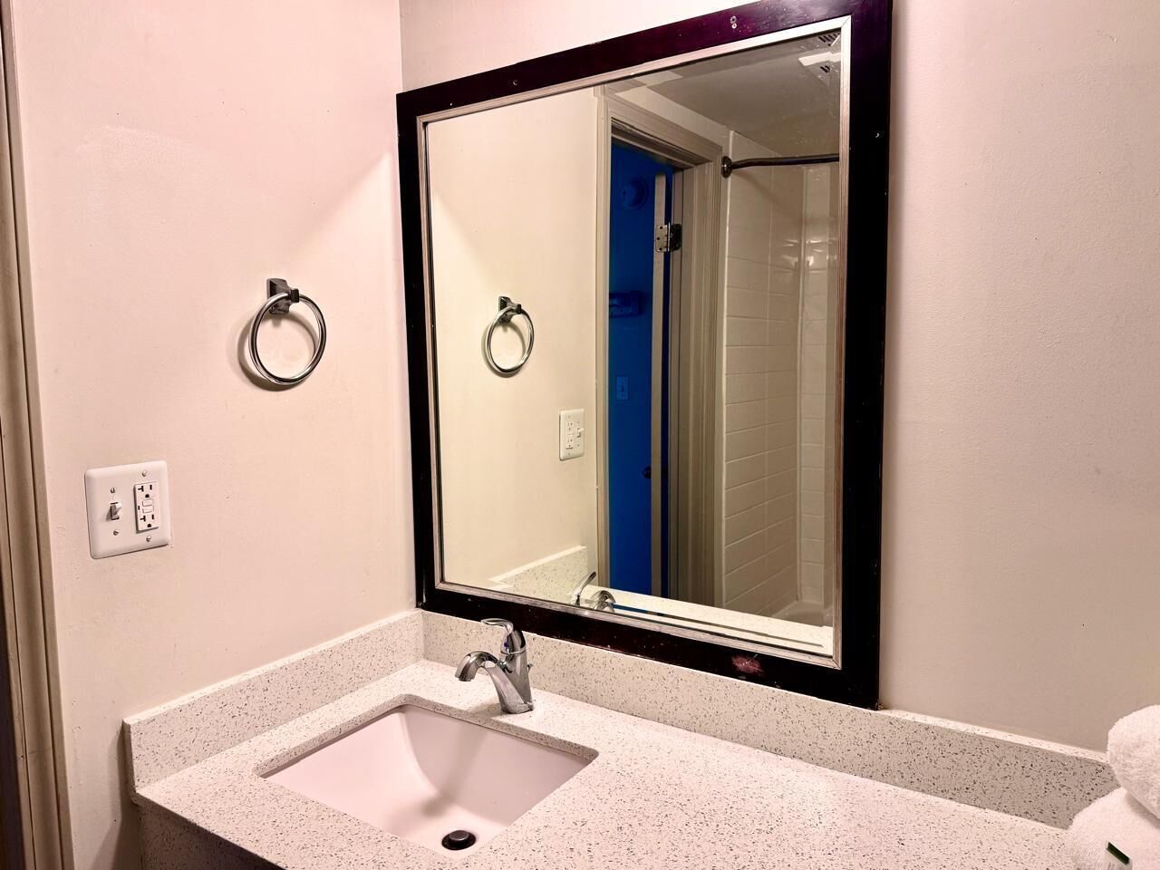 Un baño con lavamanos, espejo y tozaleta.