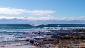Une plage rocheuse où les vagues se brisent sur le rivage.