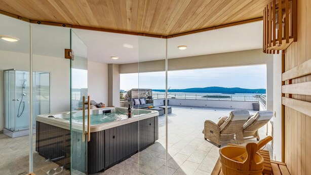 Ett modernt spaområde med ett bubbelbad, sittplatser och utsikt över havet.