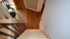 Un escalier en bois mène à une pièce dotée d’une fenêtre et d’une porte.
