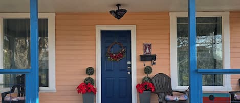 A house with a blue door, number 565, a porch with chairs, and a wreath.
