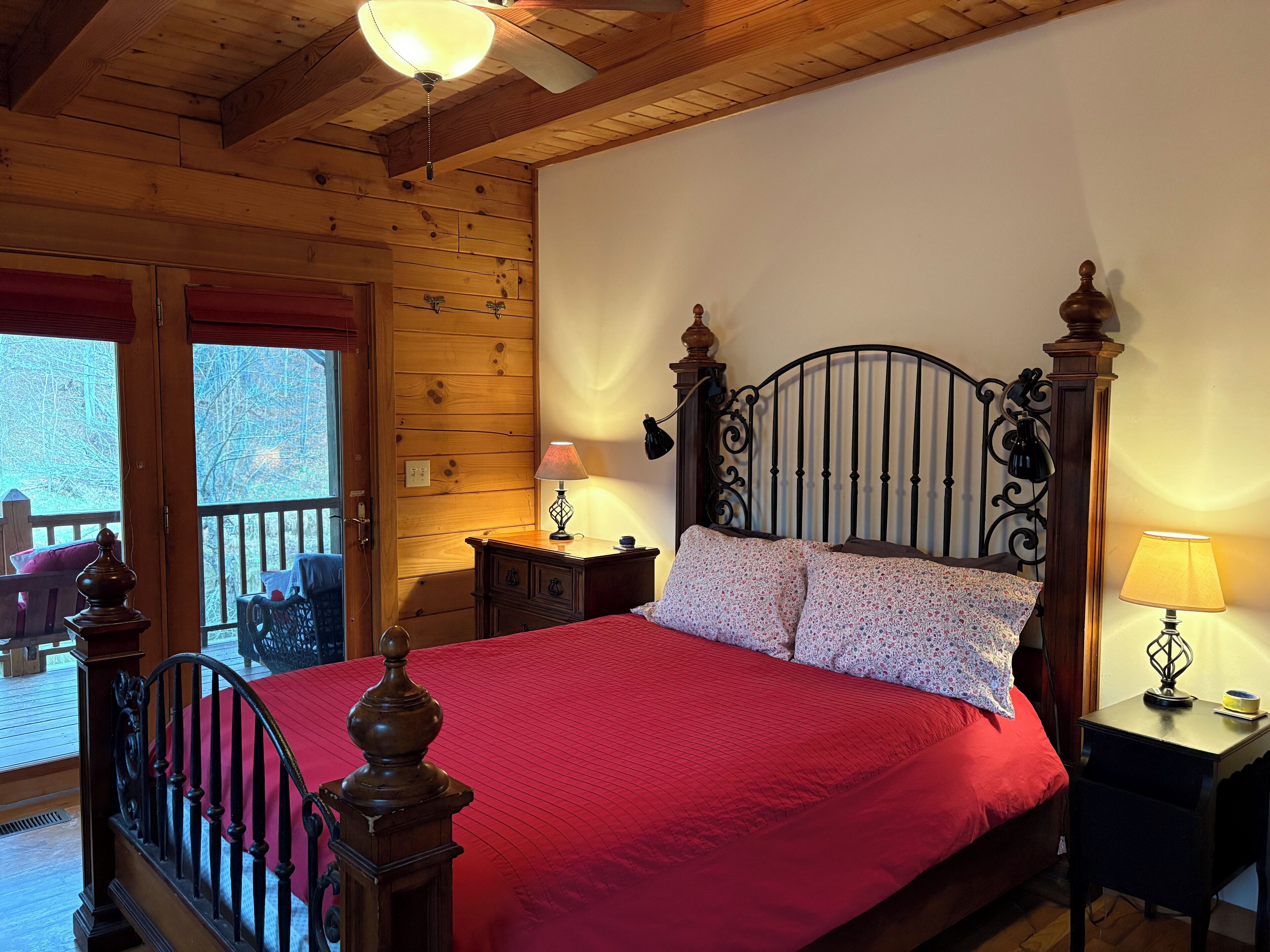 Un dormitorio con paneles de madera, una cama, dos lámparas de noche y vistas al exterior.