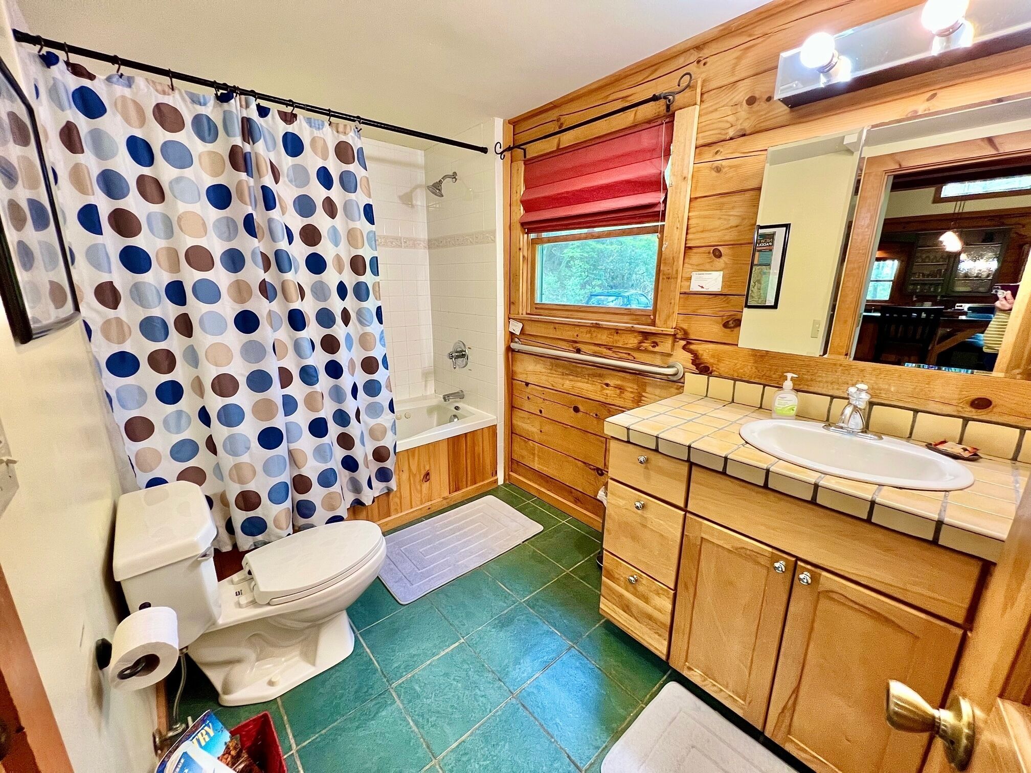 A bathroom with a shower, toilet, sink, and wooden cabinets.