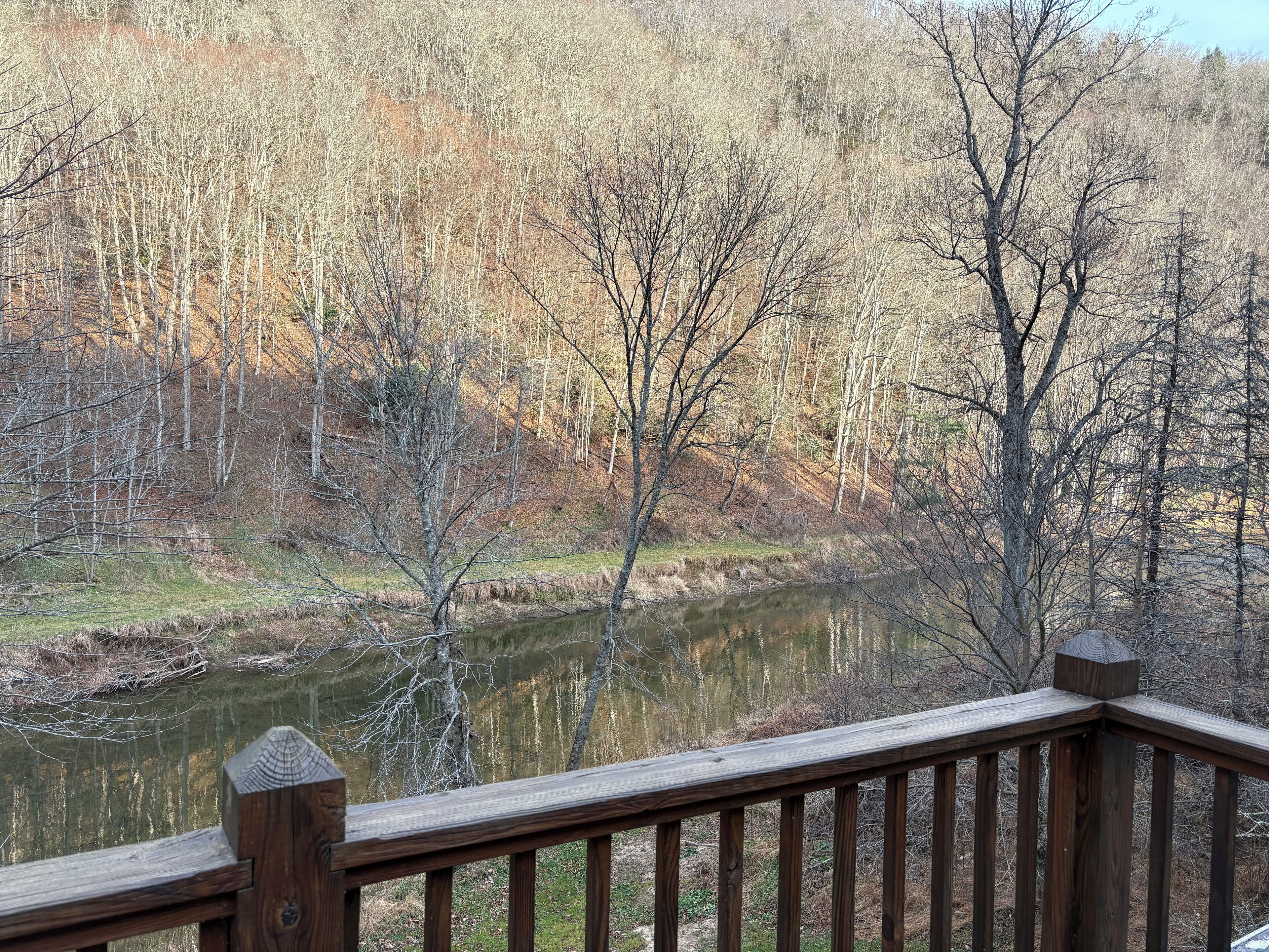 A wooden deck overlooking a river with trees in the background.