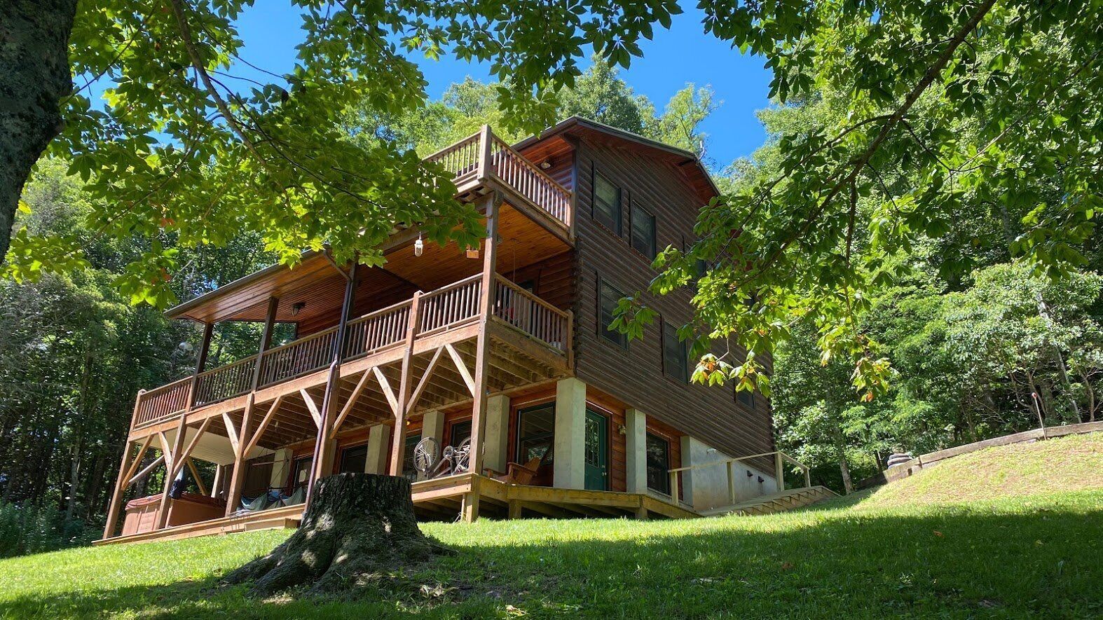 Une cabane en bois dotée d’un balcon, entourée d’arbres.