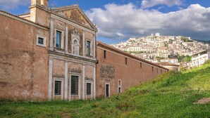 Un edificio histórico con arquitectura clásica, vistas a una colina y un paisaje urbano distante.