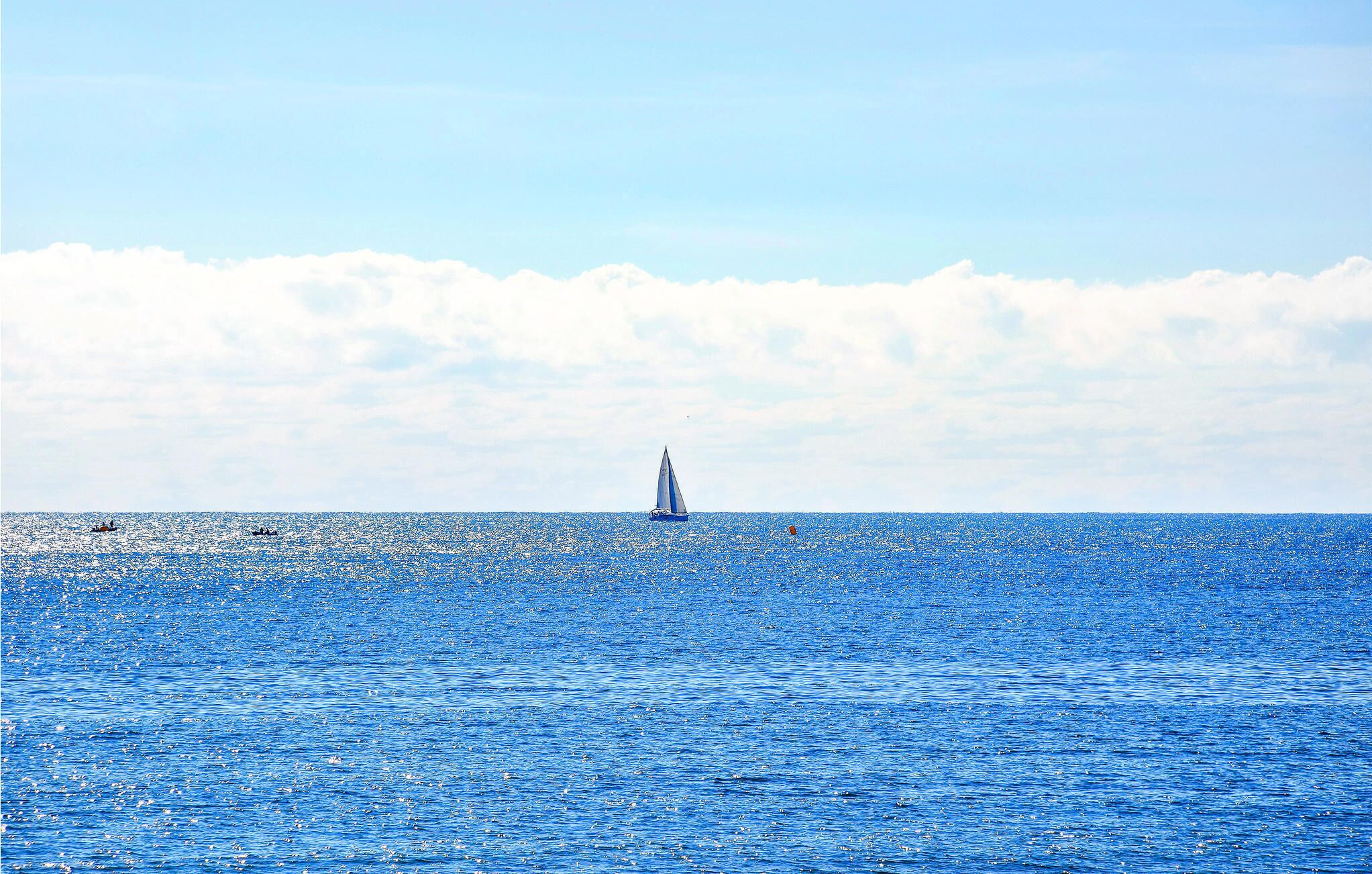 A sailboat on a calm sea with a clear sky.
