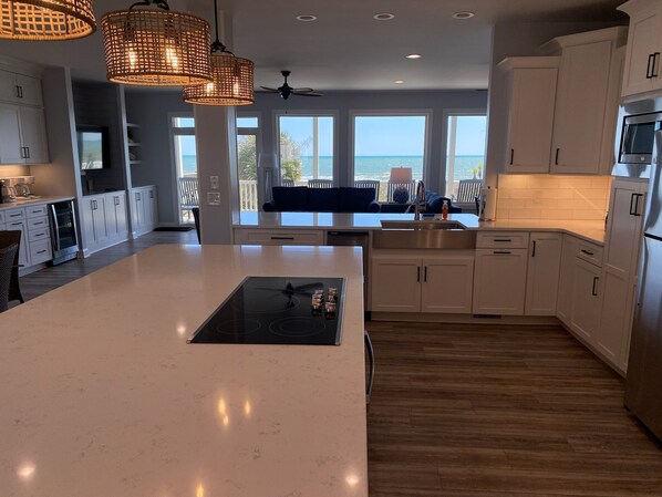 A modern kitchen with a large island, white cabinetry, and a view of the ocean.