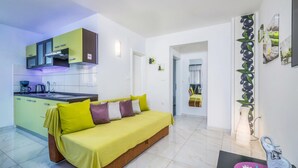 Un appartement moderne comprenant une cuisine, un canapé recouvert d’un tissu jaune et un coin repas.