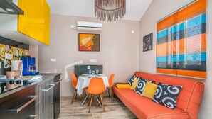 Een ruimtelijk ingerichte leefruimte met kitchenette, eethoek en zithoek.