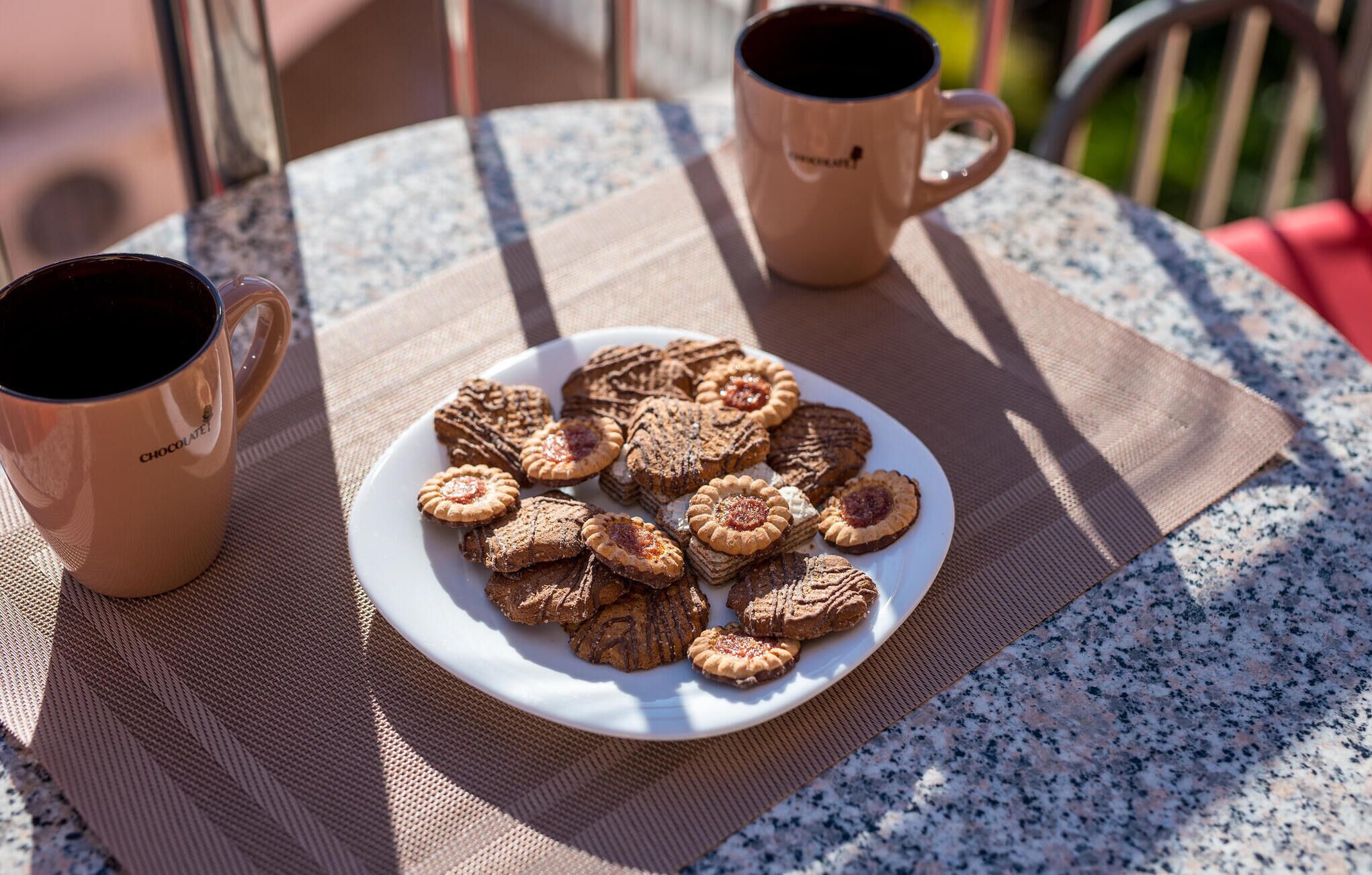 Ett bord med en tallrik kakor och två kaffemuggar.