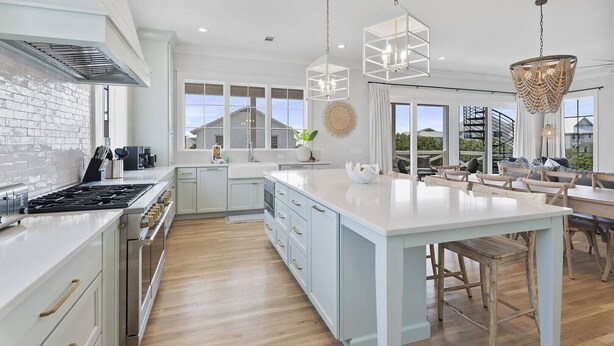 A modern kitchen with a large island, white cabinetry, and a brick backsplash. - Grayton Home with Pool, Rooftop Deck & Fire Pit (Santa Rosa Beach)