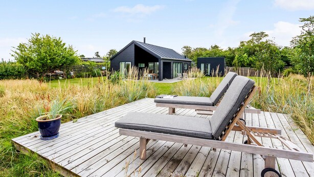 A wooden deck with two lounge chairs and a potted plant. - Stunning home in Vejby with kitchen (Vejby)