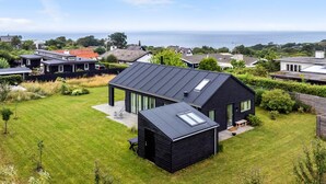 A modern house with a large glass conservatory, a spacious lawn, and a view of the sea. - Stunning home in Vejby with kitchen (Vejby)
