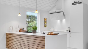 A modern kitchen with a wooden slatted island, pendant lighting, and a view of greenery outside. - Stunning home in Vejby with kitchen (Vejby)