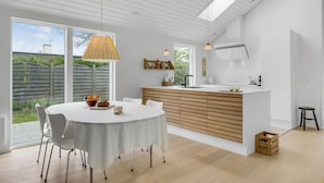 A modern kitchen with a central island, white cabinetry, and a large window providing a view of the outdoors. - Stunning home in Vejby with kitchen (Vejby)