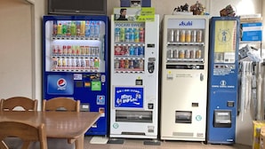 A row of vending machines with various beverages and snacks, a table, and chairs in the foreground. - Business Hotel Chateau Est Takamatsu (Takamatsu)