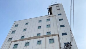 A tall, modern building with a symmetrical facade, multiple windows, and a central air conditioning unit. - Business Hotel Chateau Est Takamatsu (Takamatsu)