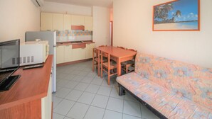 A compact kitchen with a dining table and a sofa. - Stunning apartment in Rosolina Mare (Rosolina Mare)