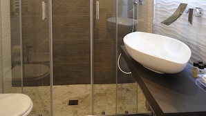 Um banheiro moderno com chuveiro em vidro, pia branca e piso revestido de azulejos.