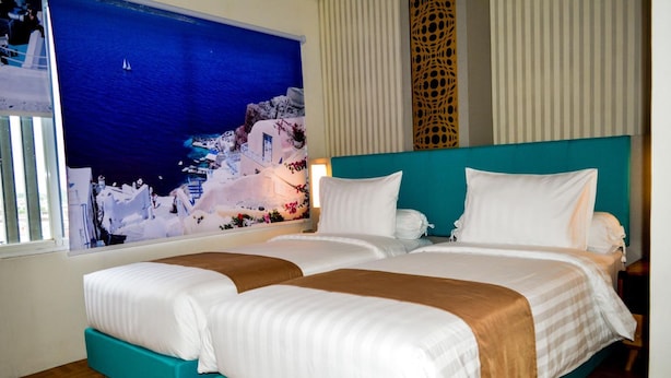 Ein Hotelzimmer mit zwei Betten, einem großen Fenster mit Meerblick und einer dekorativen Wandverkleidung.