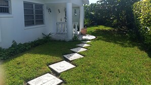A white house with a tiled pathway leading to a porch. - Spacious Apartment with Essential Utensils for Cooking and Relaxation (nassau)