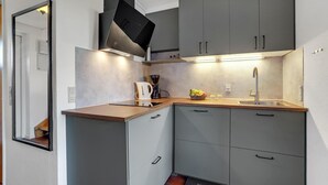 Une cuisine compacte avec des meubles gris, un plan de travail en bois, une cuisinière encastrée et un évier.